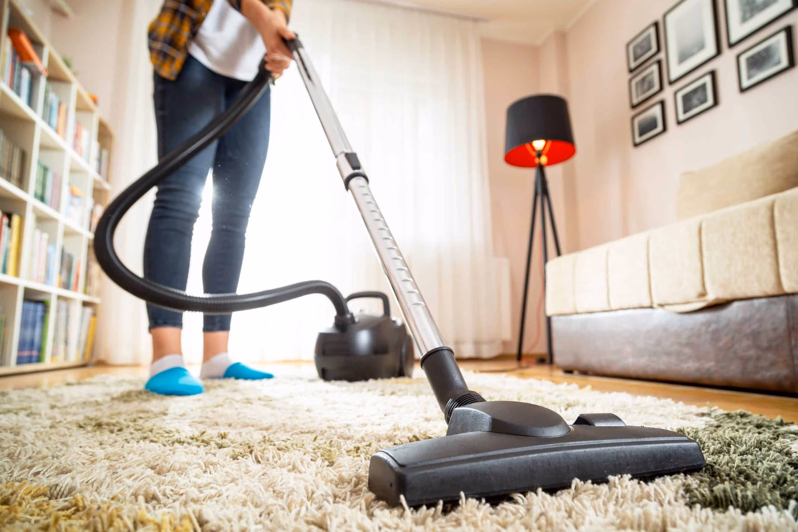 Support worker vacuuming a living room floor in a tidy home