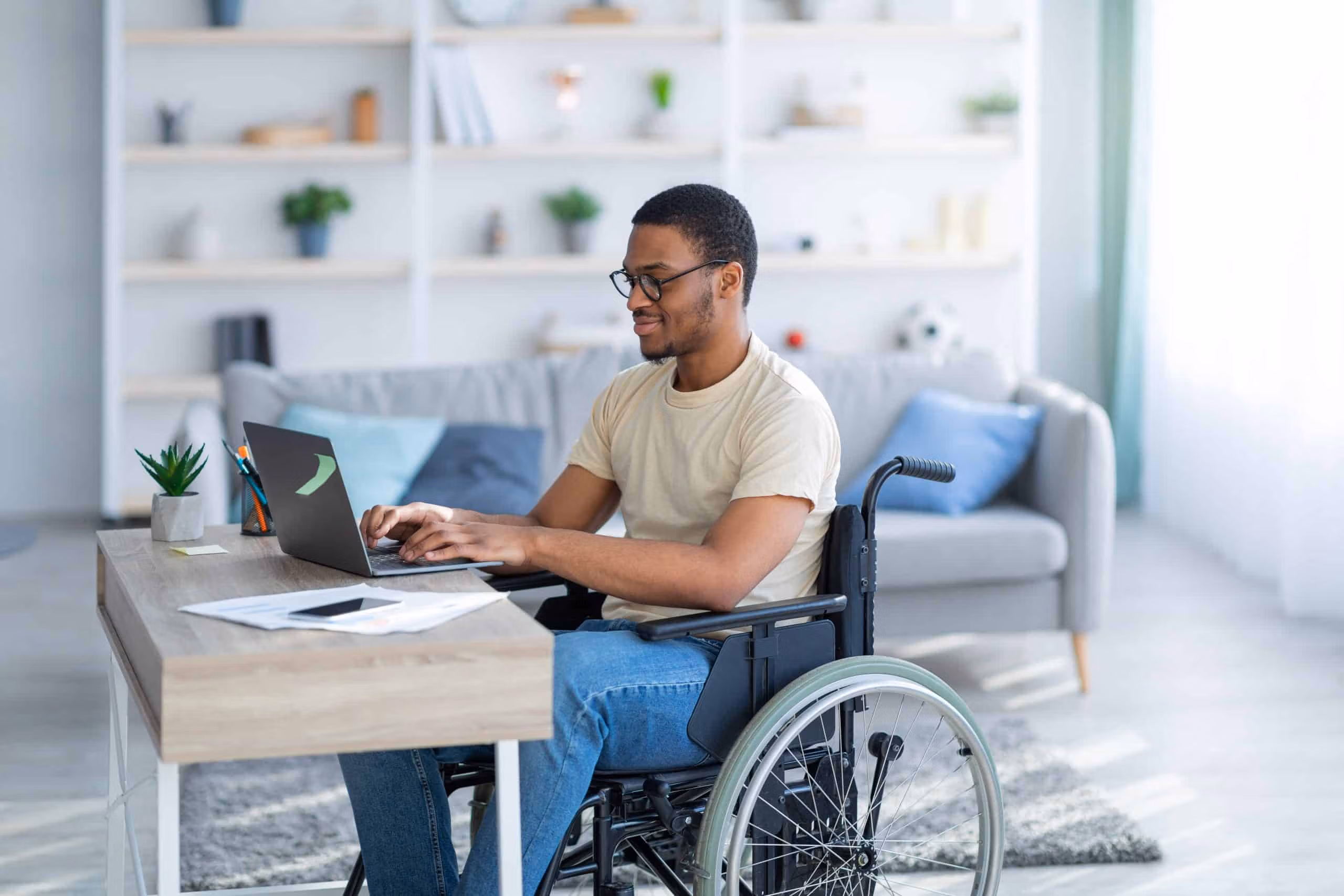 Participant in a wheelchair working on a laptop in a home office