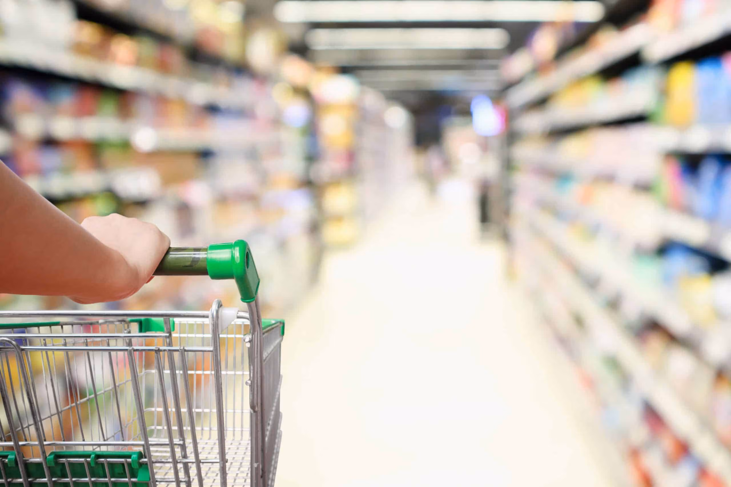 View from behind a trolley being pushed through a supermarket aisle