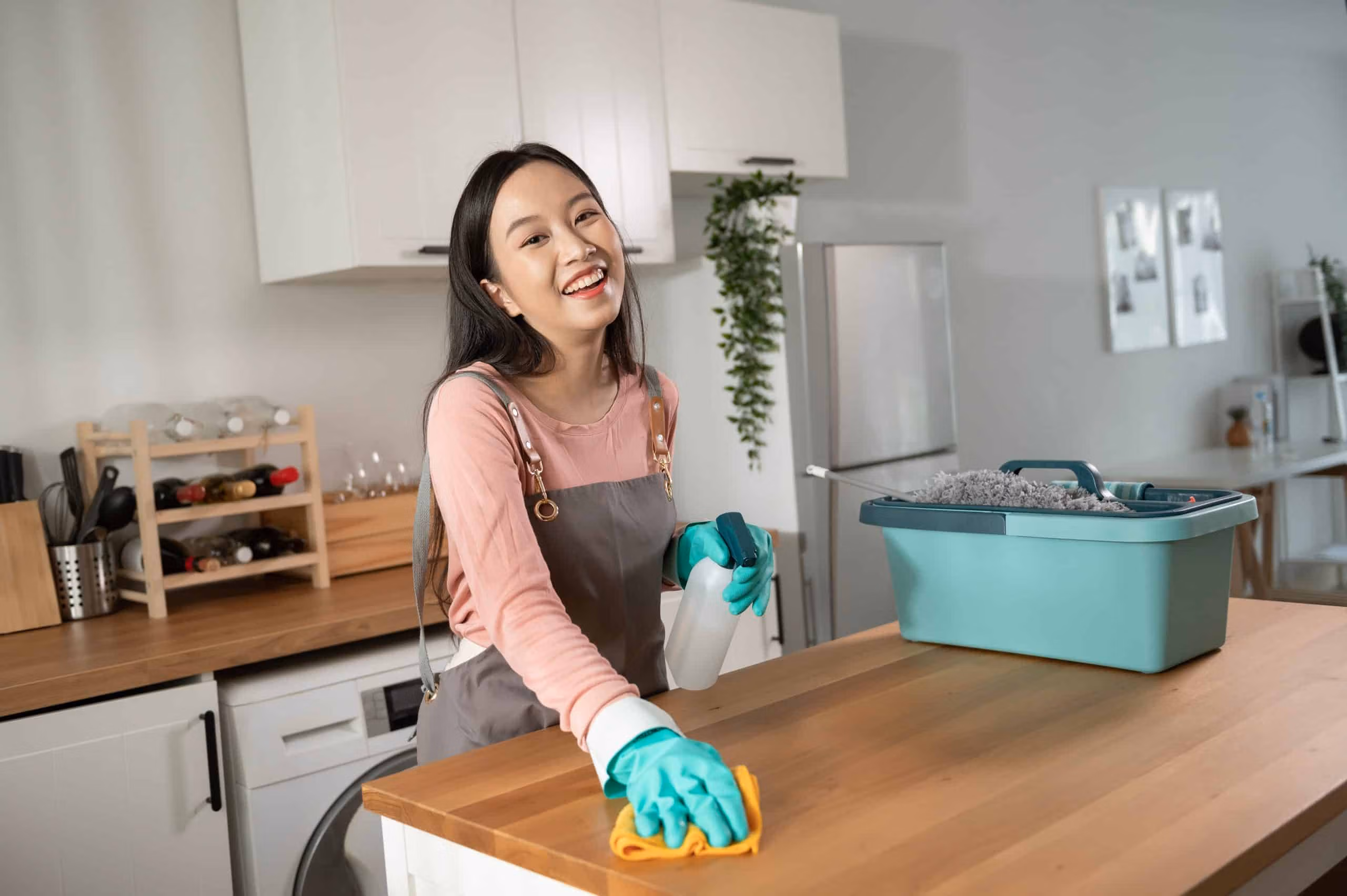 Support worker smiling while wiping a kitchen bench with cleaning gloves on
