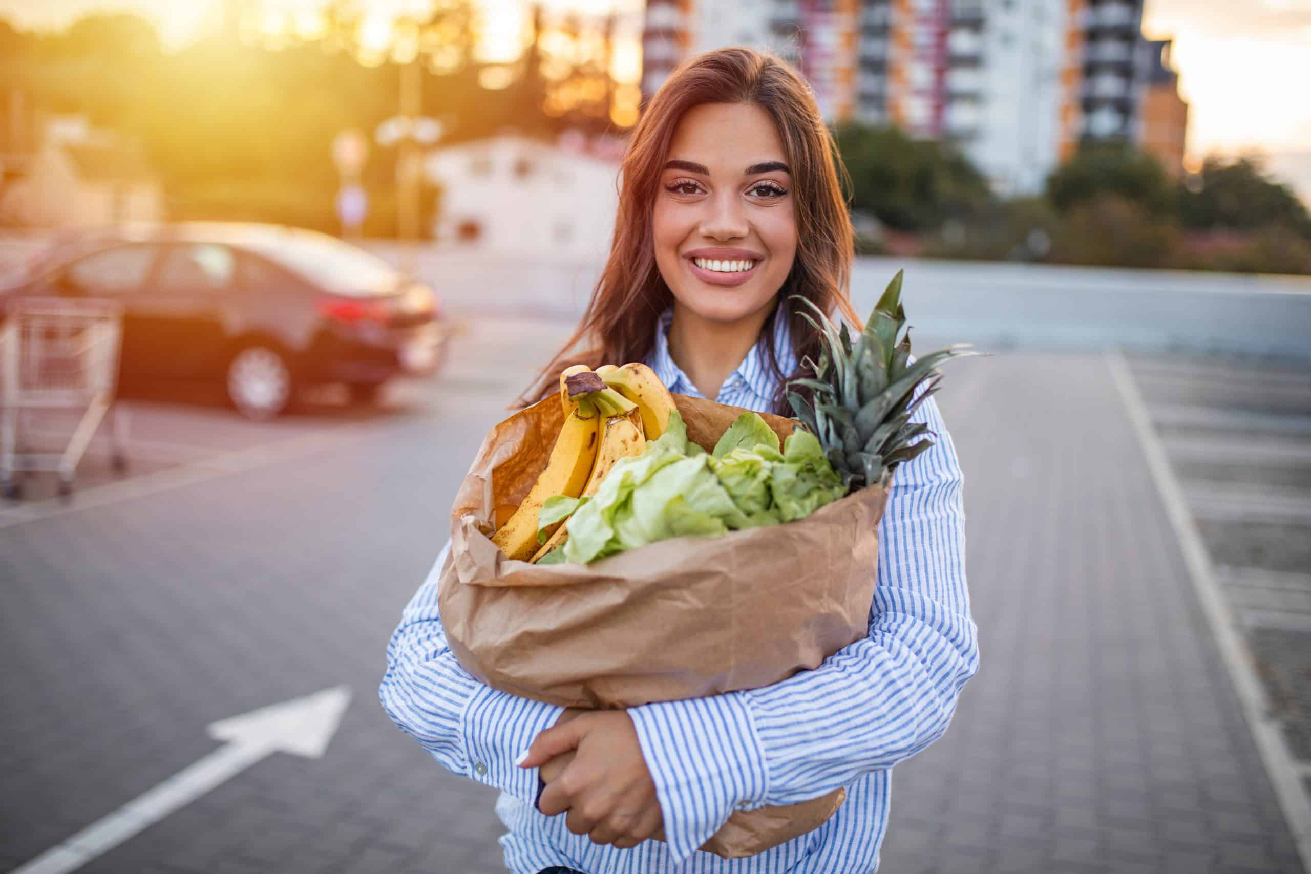 A support worker on a grocery run with a participant, holding a shopping bag of vegetables
