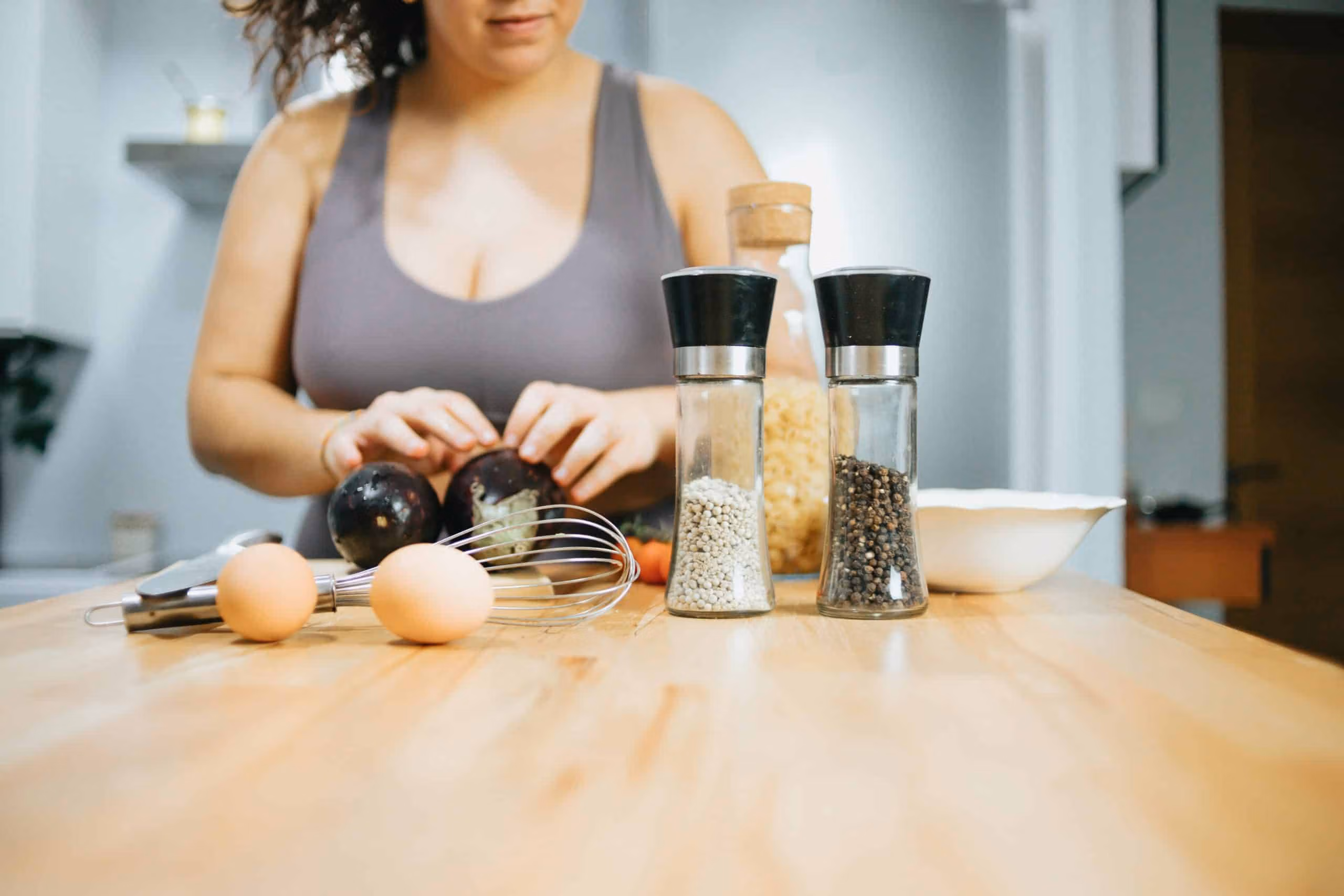 Support worker chopping vegetables on a wooden bench with spices and cooking tools in the kitchen.