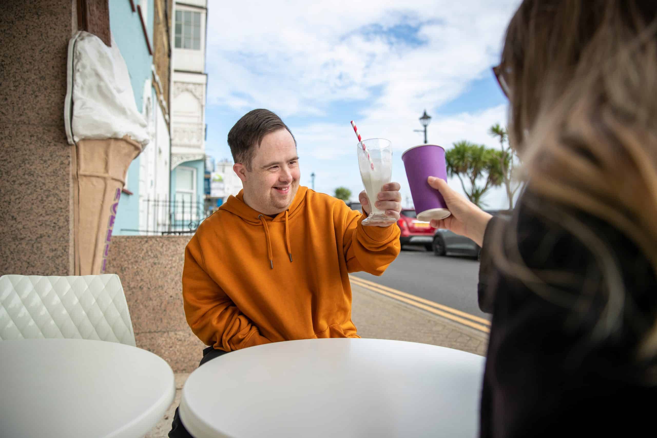 A participant and support worker out for a milkshake
